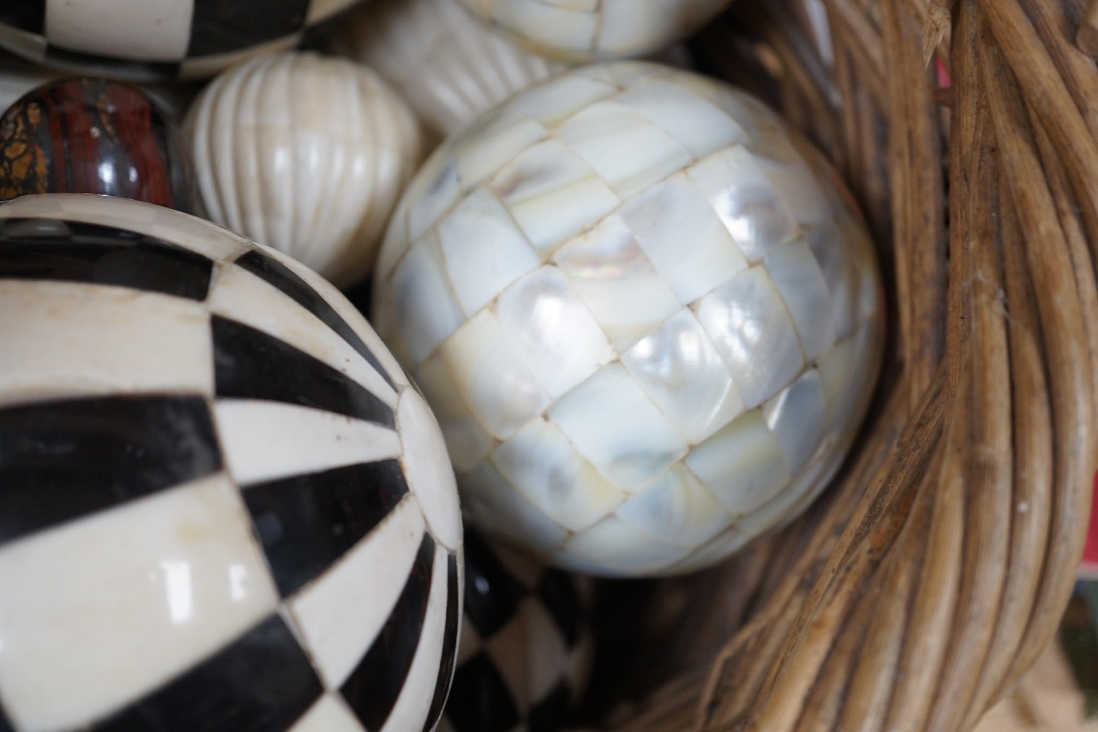 A basket of mother of pearl or bone veneered balls and other decorative balls